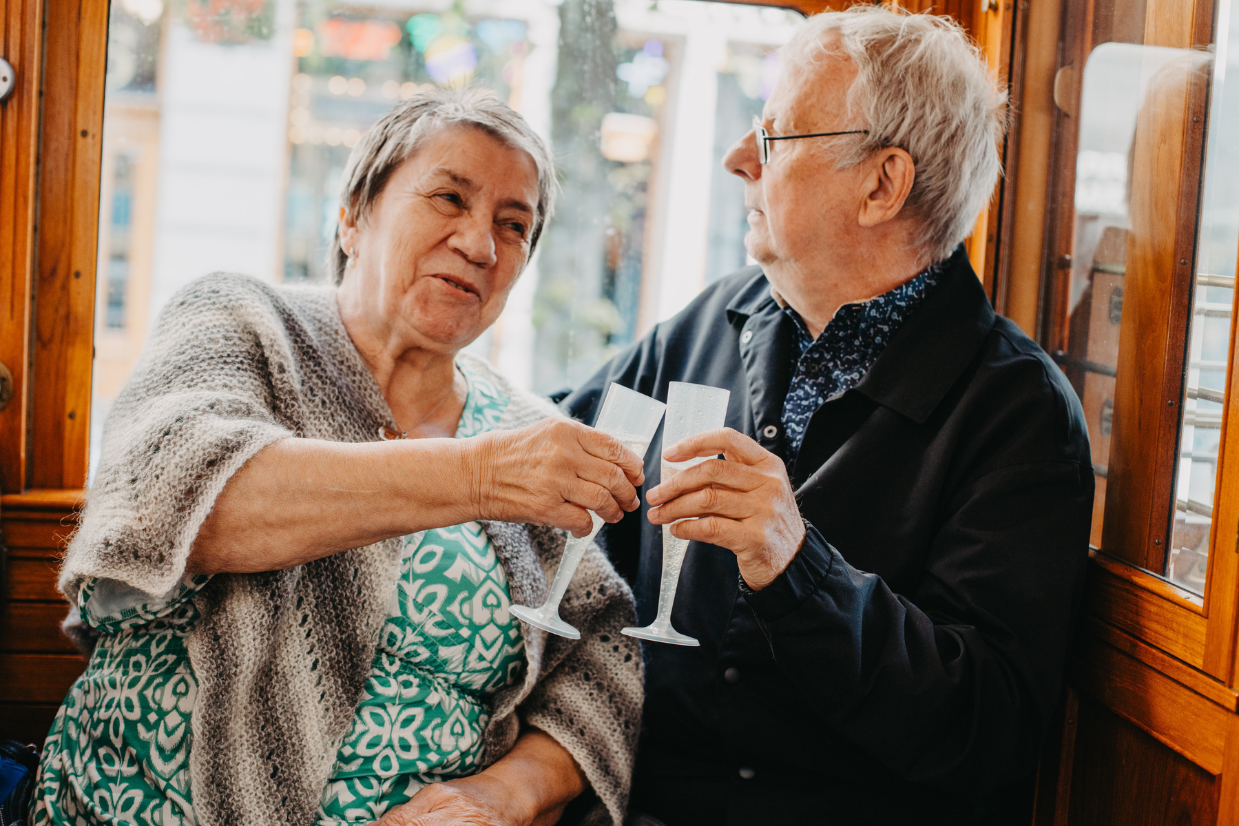 Auto-generated description: An elderly couple enjoys a toast together in a cozy, wooden setting.