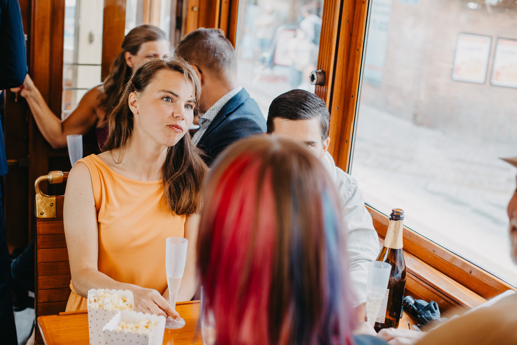 Auto-generated description: A group of people is sitting around a table in a cafe, engaging in conversation and enjoying snacks and drinks.