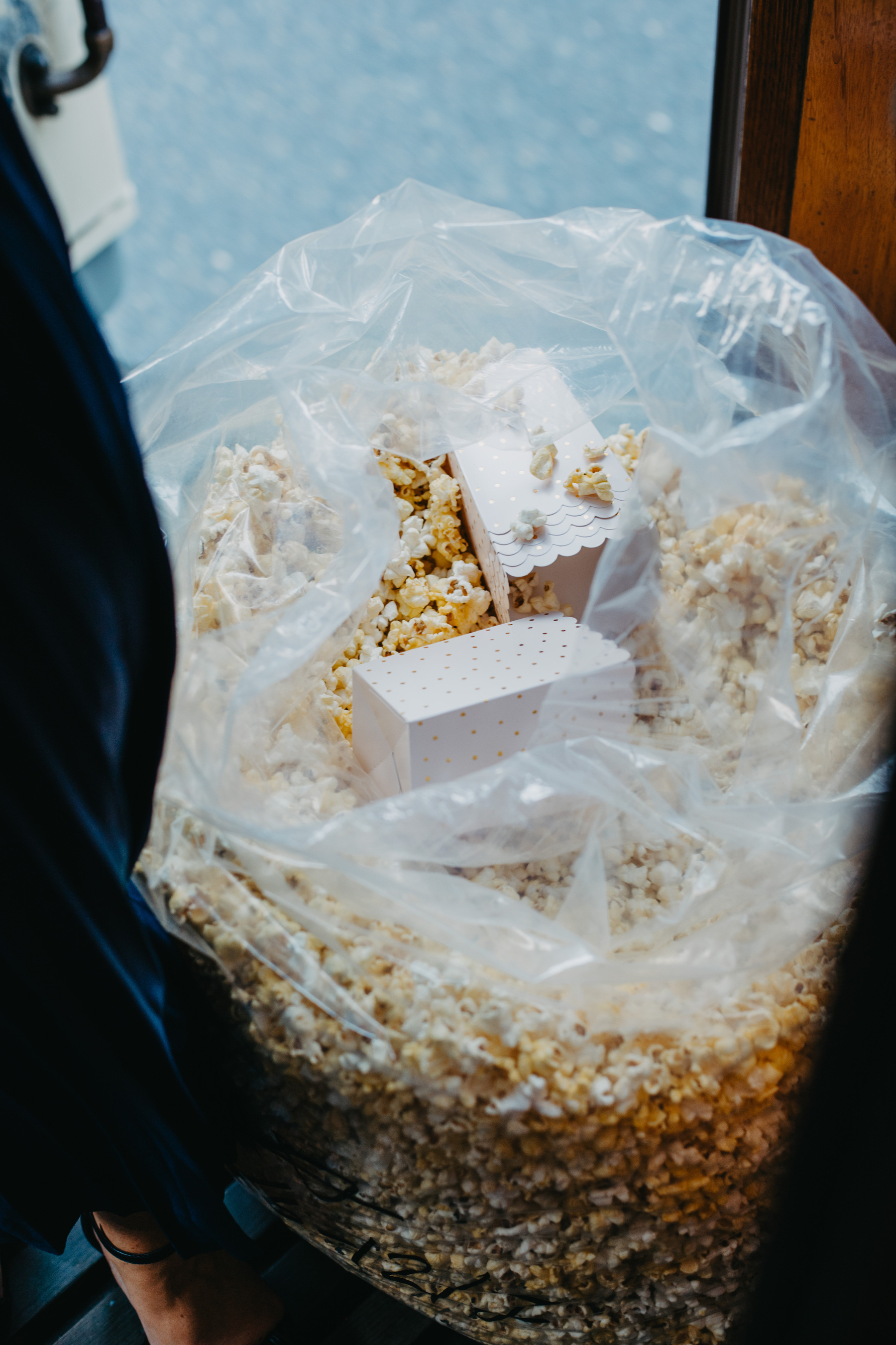 Auto-generated description: A large plastic bag filled with popcorn contains a few small, white, decorated boxes placed inside it.