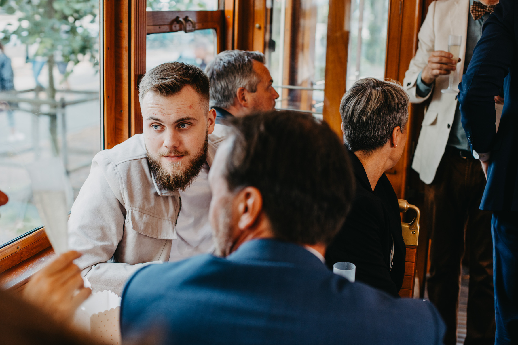 Auto-generated description: Several people are seated and conversing inside what appears to be a restaurant or café with wooden interior decor.